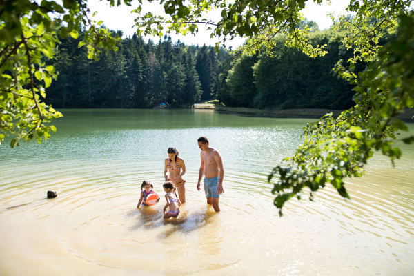 Young mother and father with their daughters in the the lake. Summer heat and water.