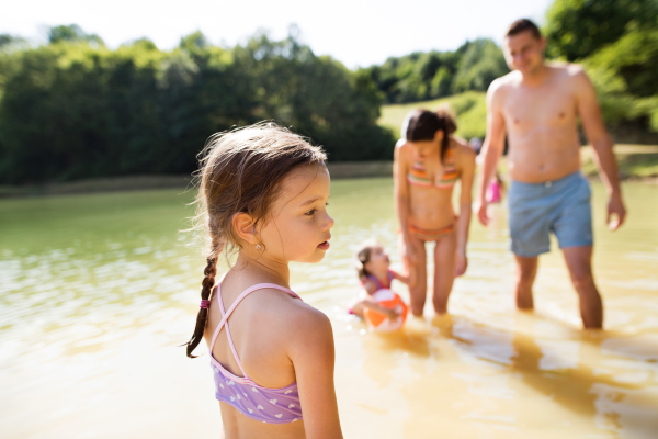 Young mother and father with their daughters in the the lake. Summer heat and water.