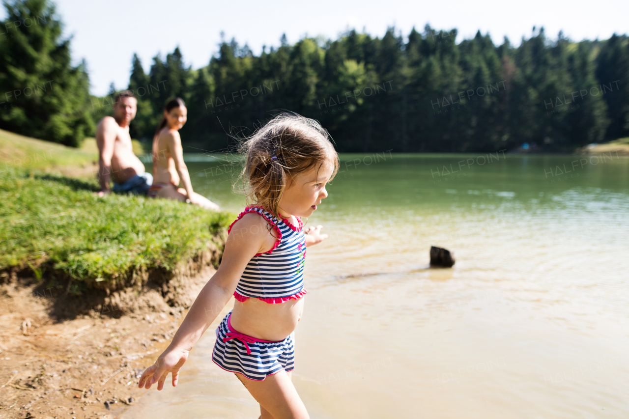 Young mother and father with their daughter at the the lake. Summer heat and water.