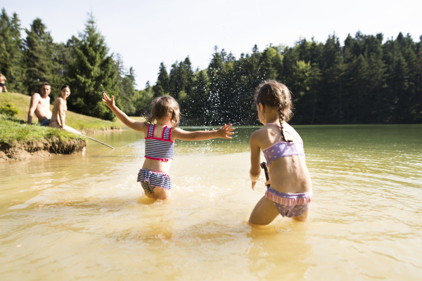 Young mother and father with their daughters at the the lake. Summer heat and water.