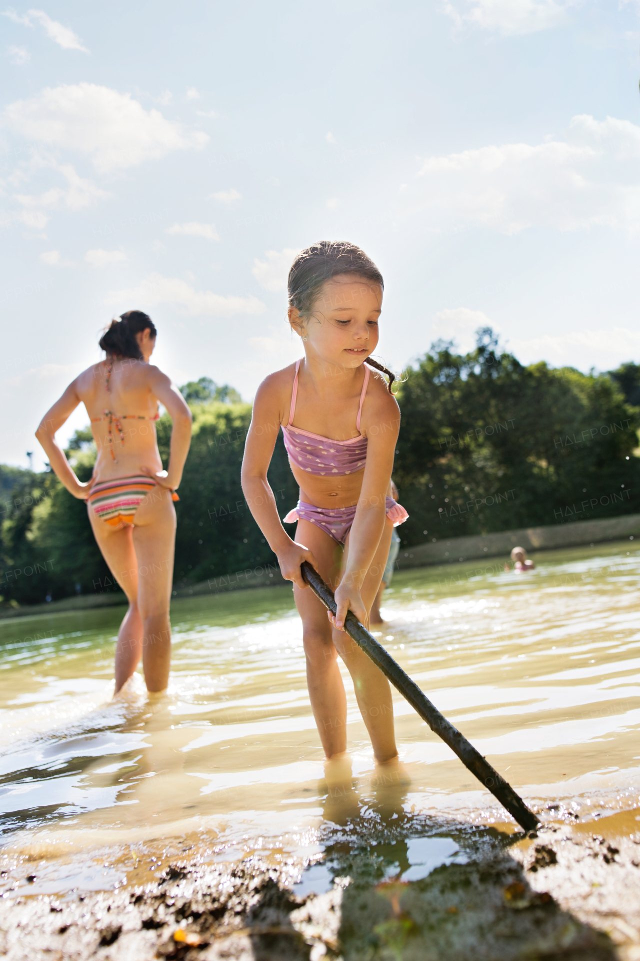 Beautiful young mother and cute little daughter in the the lake. Summer heat and water.