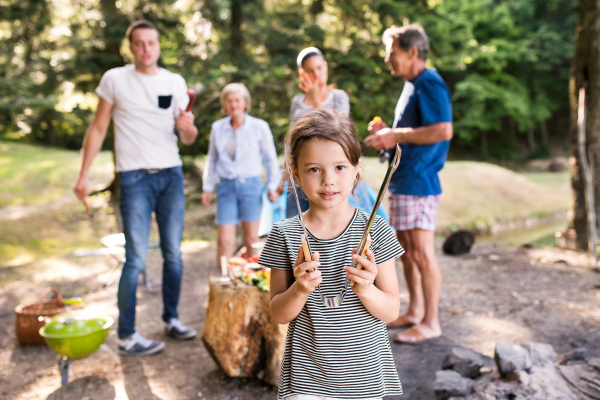 Beautiful family enjoying camping vacation in forest. Barbecue with drinks and food.