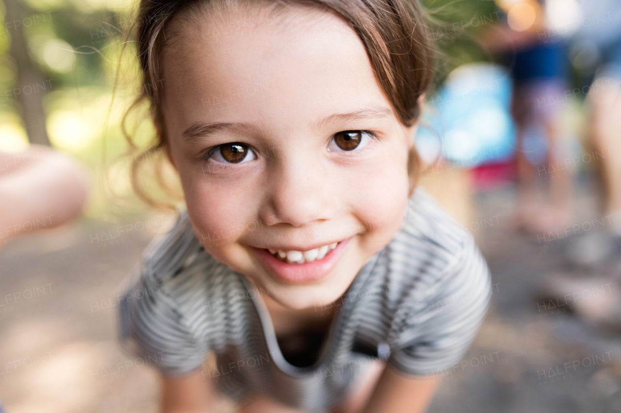 Face of cute little girl outdoors in nature camping with her family.