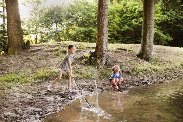 Cute little girls standing in the the lake playing. Summer heat and water.