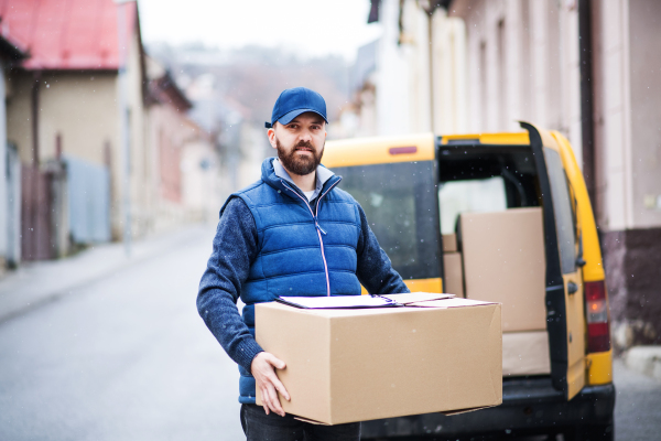 Delivery man delivering parcel box to recipient - courier service concept.