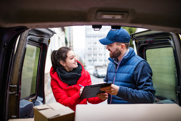 Young woman receiving parcel from delivery man - courier service concept.