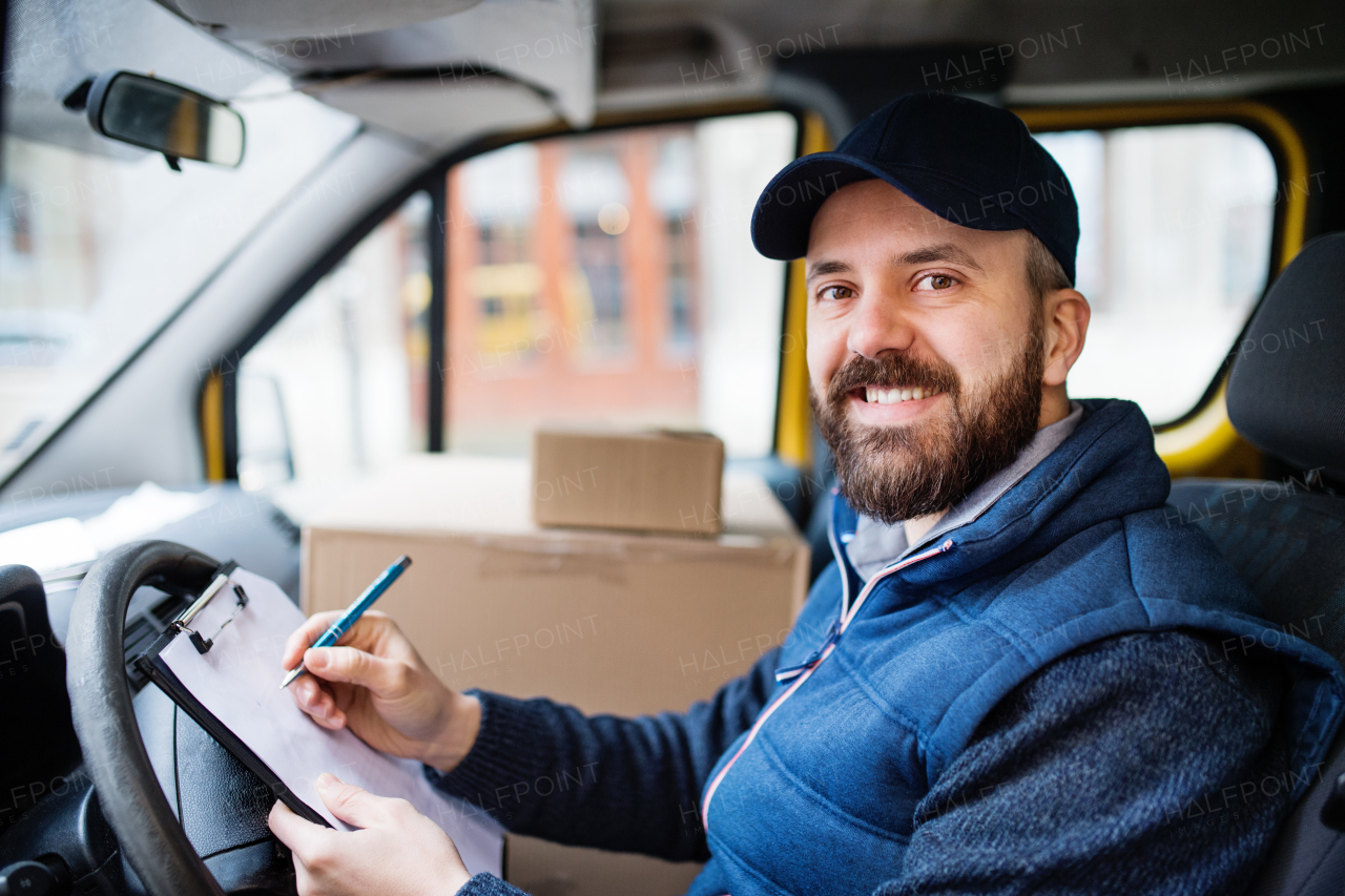 Delivery man delivering parcel box to recipient - courier service concept. A man signing a document.