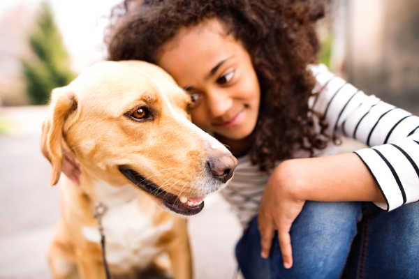 Close up of beautiful african american girl with curly hair outdoors with her cute dog.