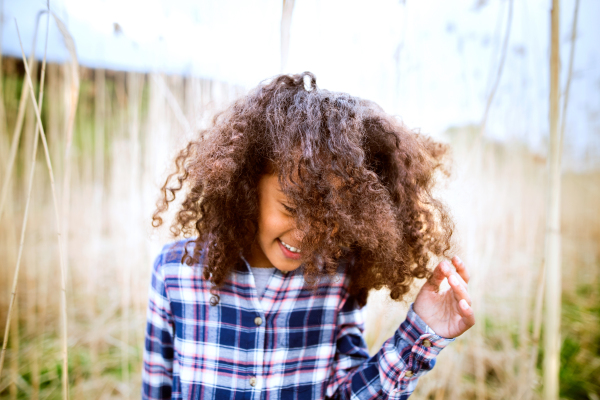 Beautiful african american girl with curly hair in checked shirt outdoors in field.