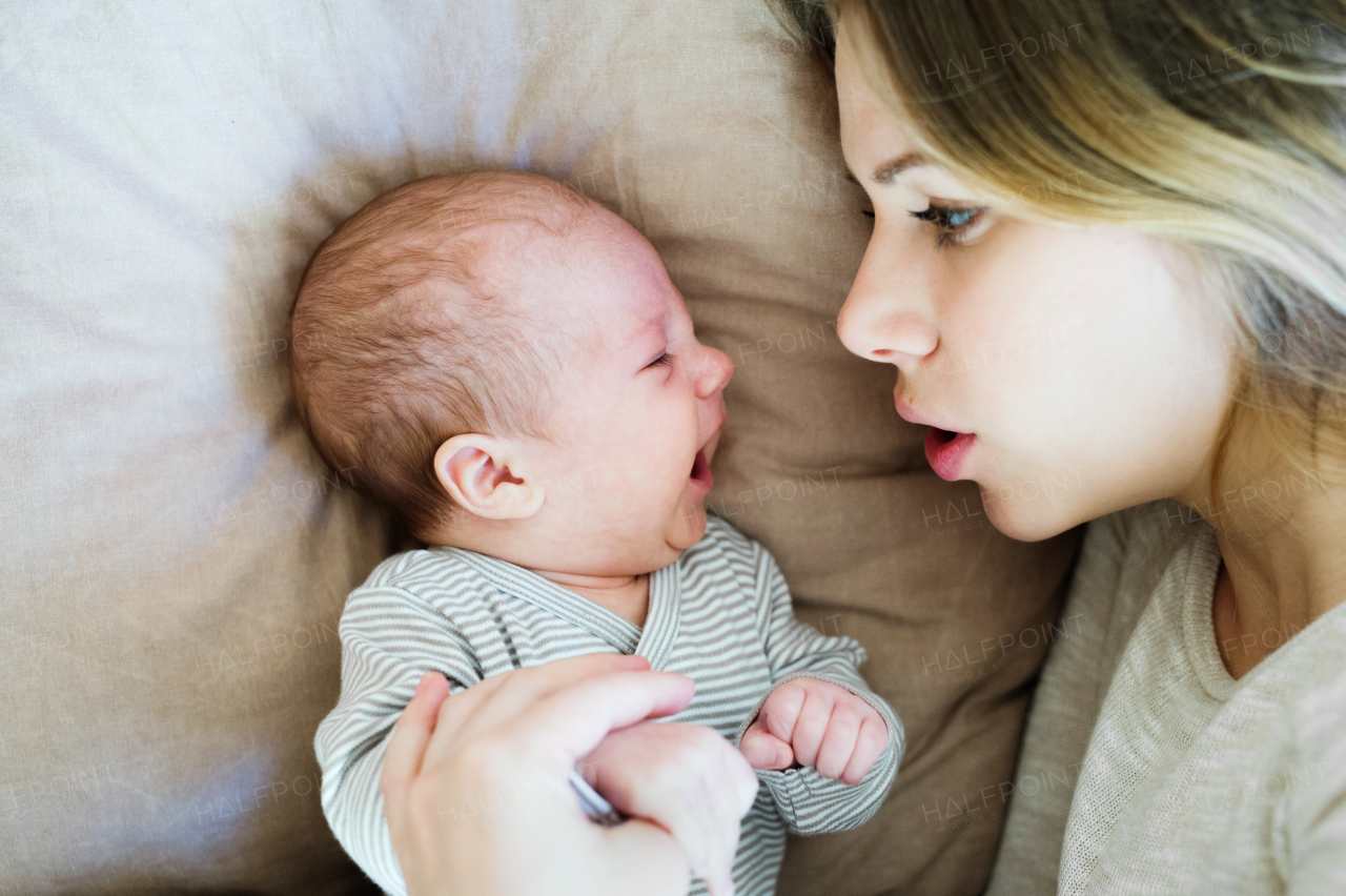 Beautiful young mother with her cute baby son lying on bed in bedroom