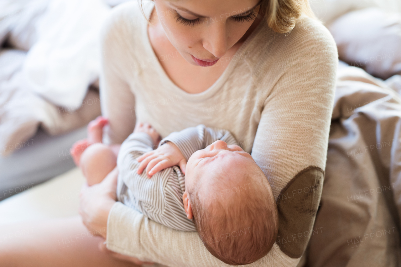 Beautiful young mother holding her baby son in her arms