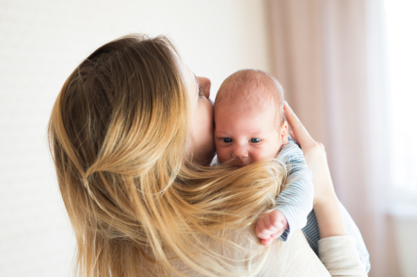 Unrecognizable young mother holding her baby son in her arms