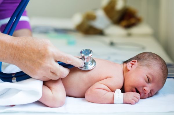 Unrecognizable doctor with stethoscope listening to hearbeat of cute newborn baby