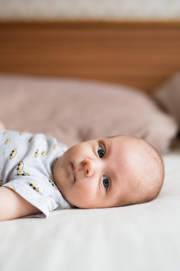 Cute newborn baby boy lying on bed, close up of his face