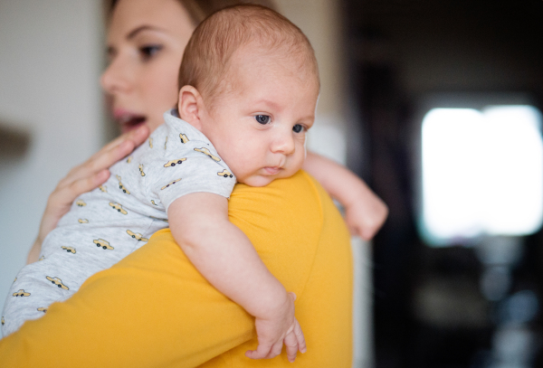 Beautiful young mother in yellow t-shirt holding her baby son in her arms