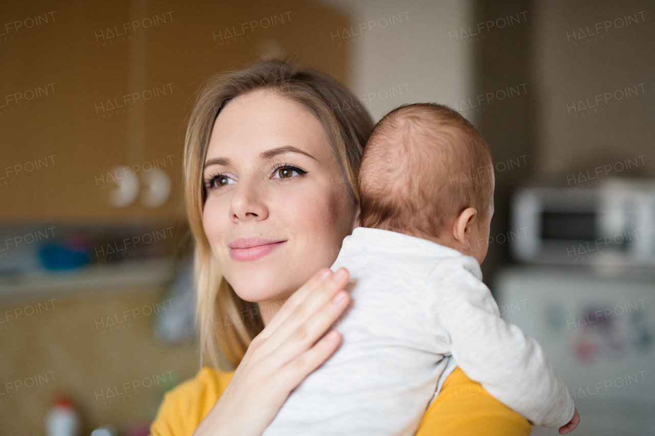 Beautiful young mother in yellow t-shirt holding her baby son in her arms