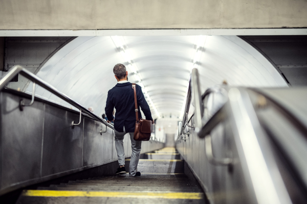 Rear view of hipster businessman walking down the stairs in subway in the city, travelling to work.