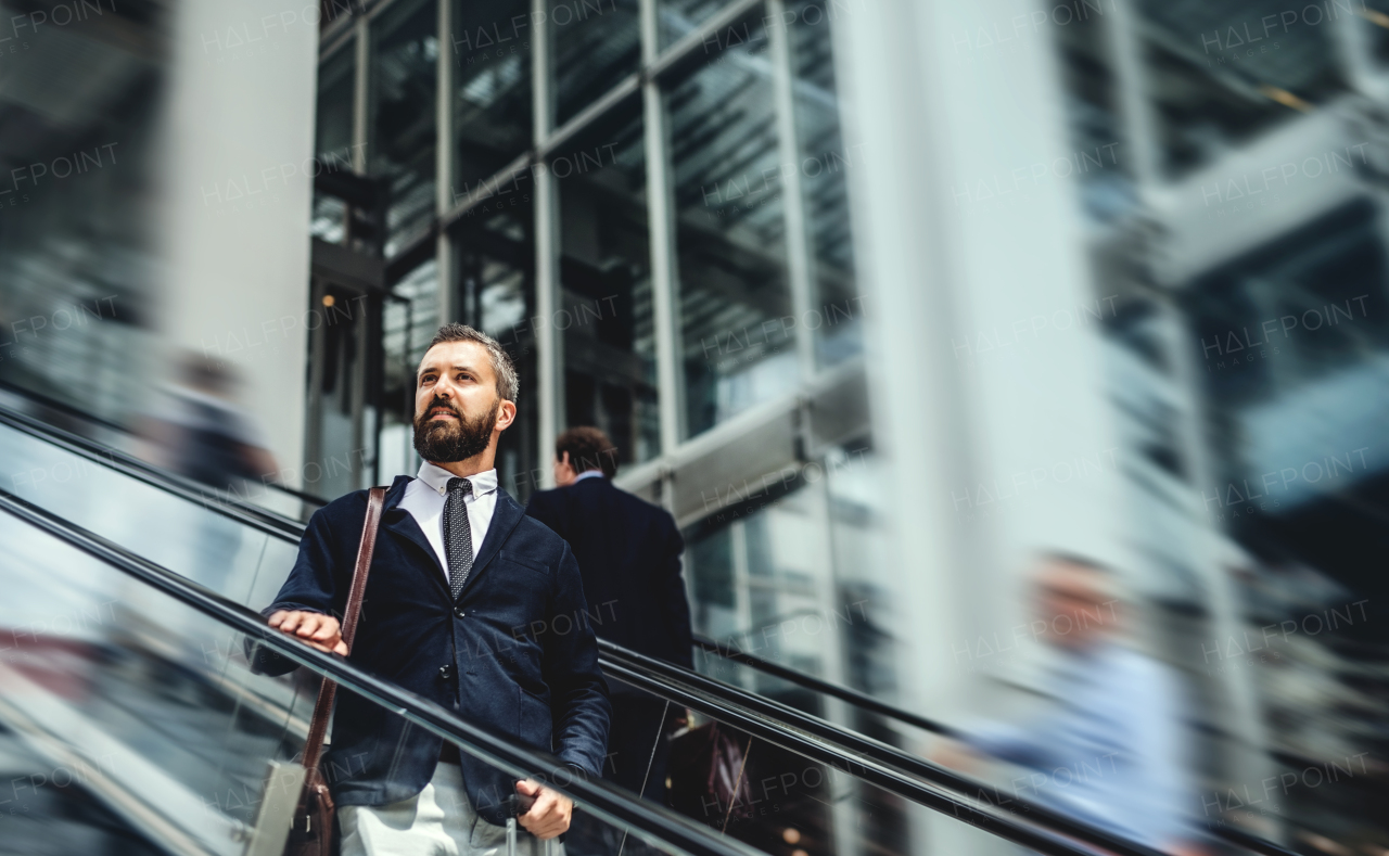 Hipster businessman using escalator in city, travelling to work. Copy space.