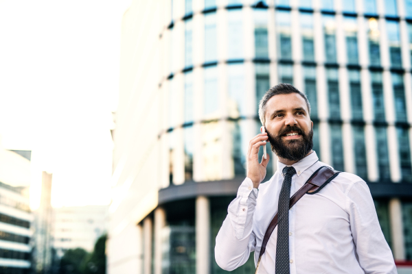 A close-up of hipster businessman with smartphone in the city, making a phone call. Copy space.