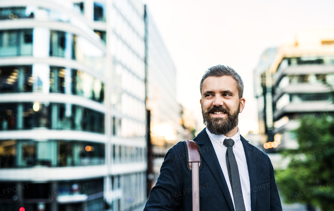 Hipster businessman standing on the street in the city at sunset. Copy space.