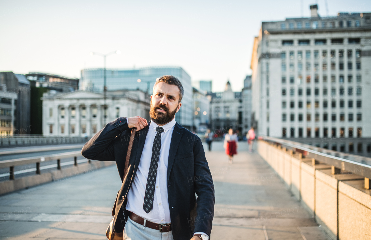 Hipster businessman walking on the street in the city at sunset.