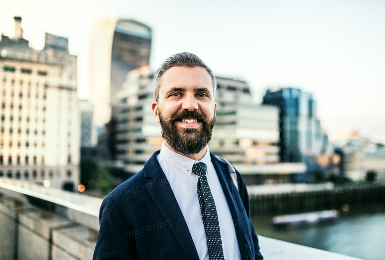 Hipster businessman walking on the bridge in the city at sunset. Copy space.