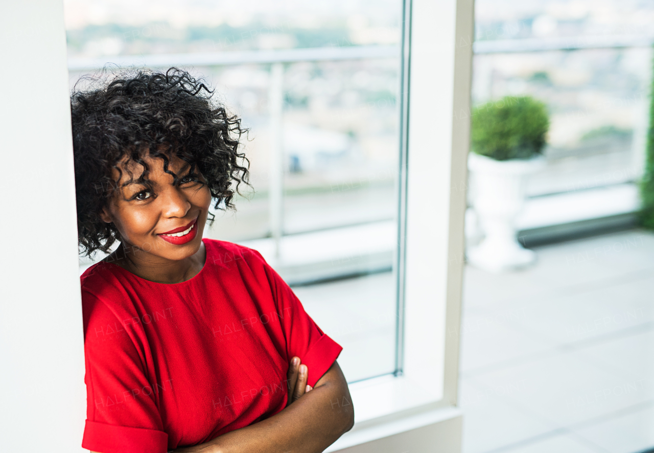 A portrait of woman standing by the window in an office. Copy space.