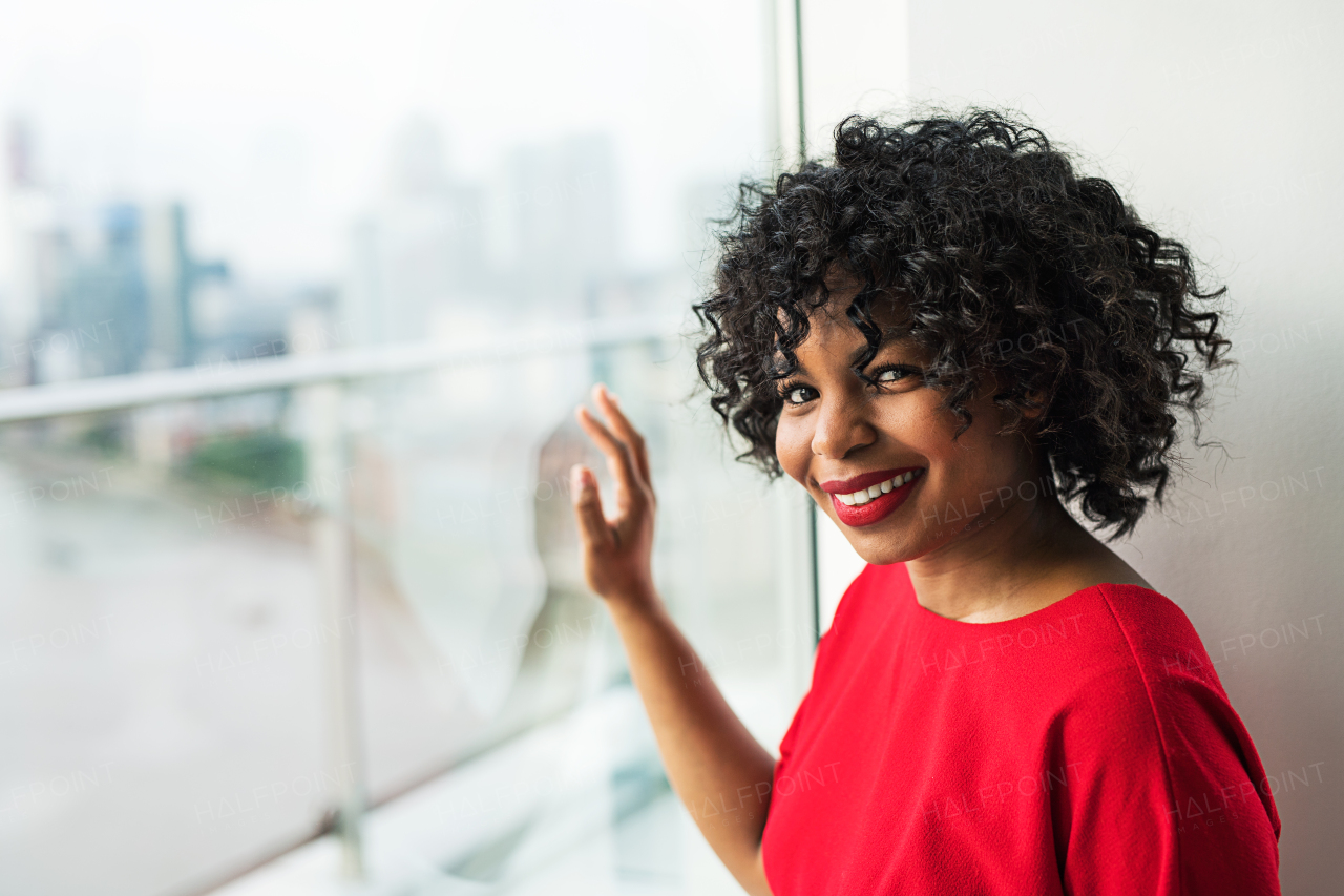 A portrait of woman standing by the window against London rooftop view panorama. Copy space.