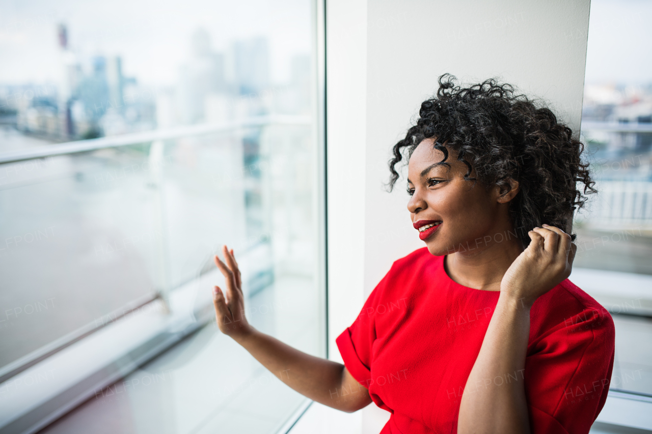 A portrait of woman standing by the window against London rooftop view panorama. Copy space.