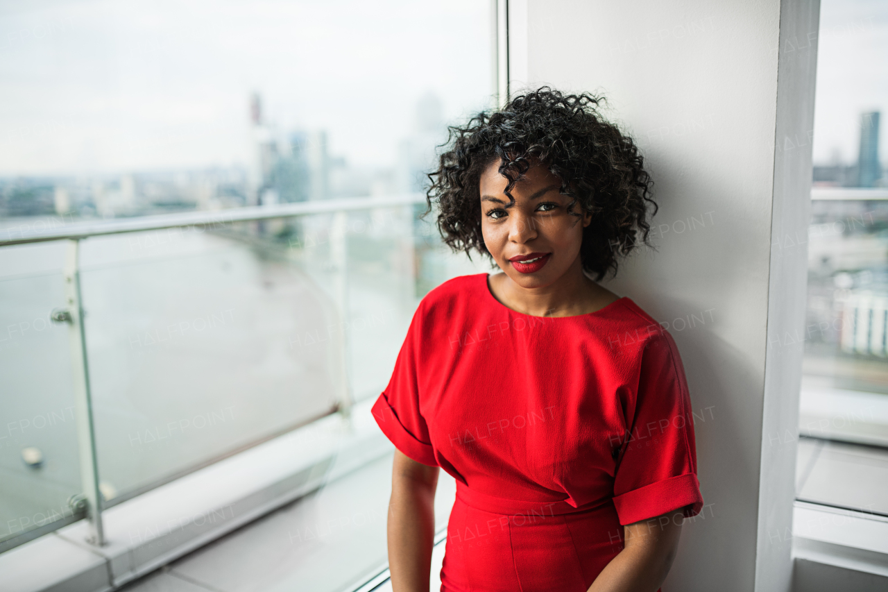 A portrait of woman standing by the window against London rooftop view panorama. Copy space.