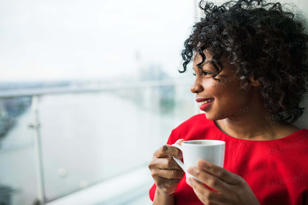 A close-up of a woman standing by the window holding a cup of coffee. Copy space.