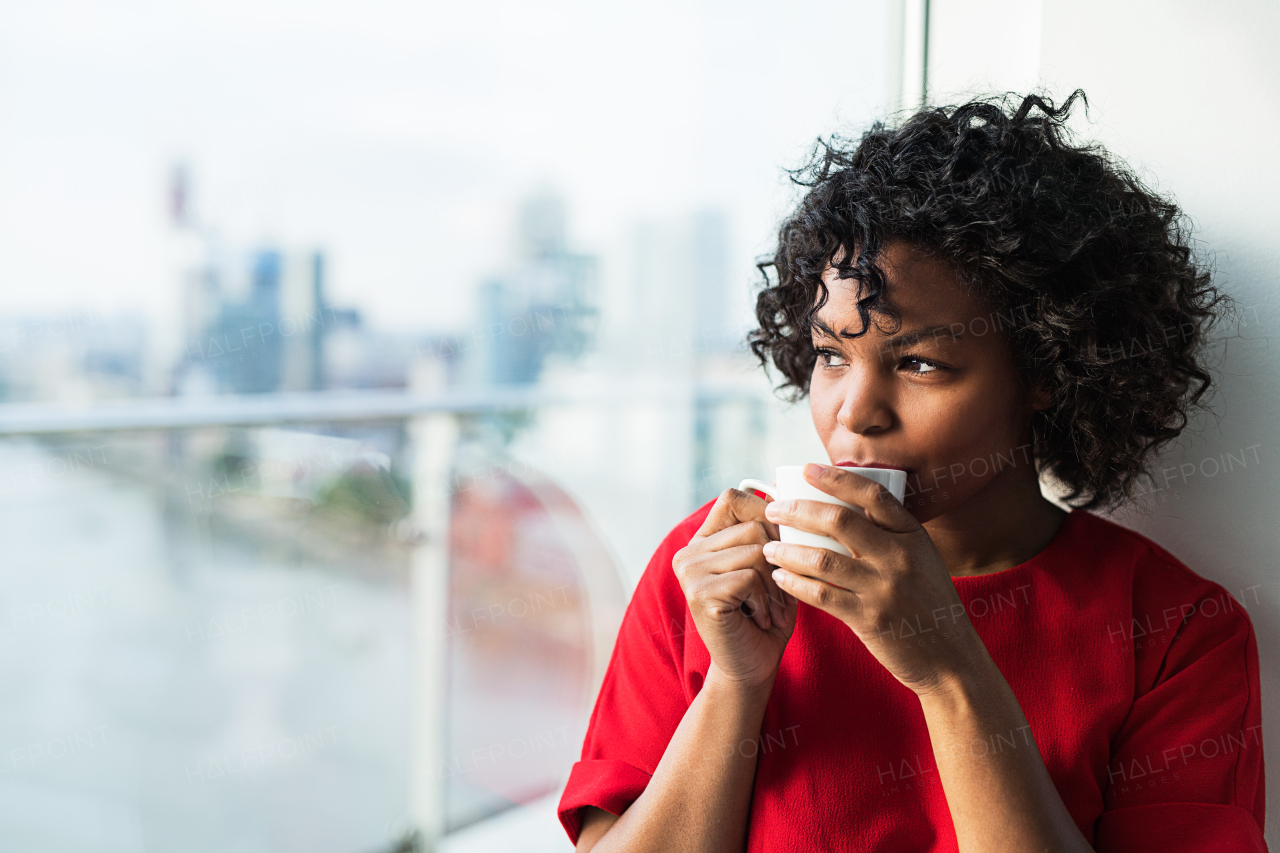 A close-up of a woman standing by the window drinking coffee. Copy space.