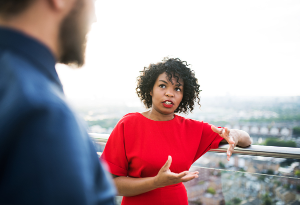 Two businesspeople standing against London rooftop view, leaning on a railing.