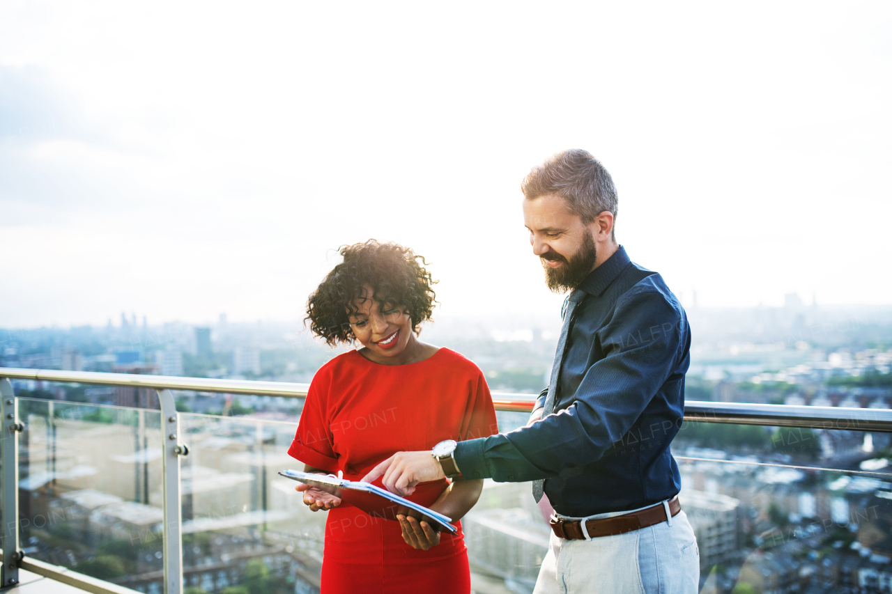 A portrait of businesspeople standing against London rooftop view, discussing issues.