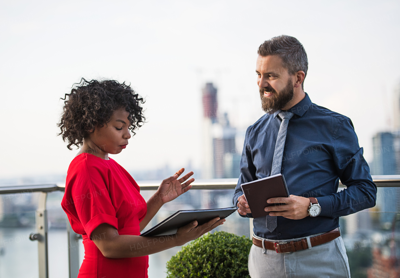 A portrait of businesspeople standing against London rooftop view, discussing issues.