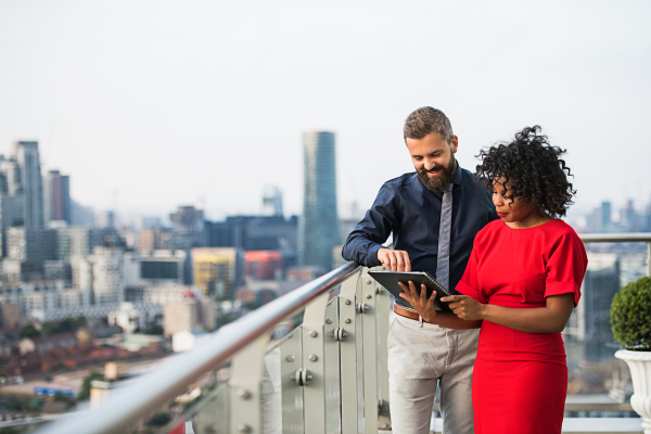 A portrait of businesspeople standing against London rooftop view, discussing issues.