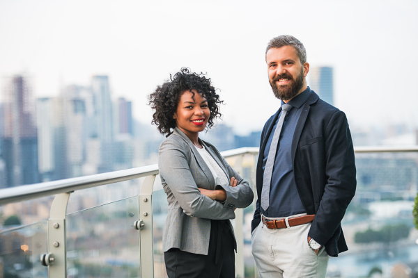 A portrait of businesspeople standing against London rooftop view.