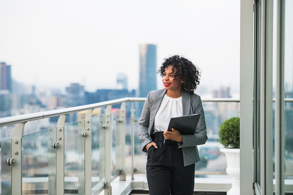 A portrait of a businesswoman with clipboard walking on a terrace in London. Copy space.