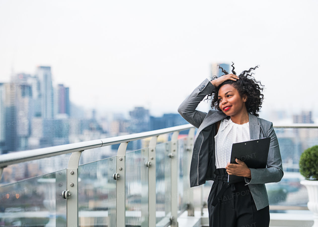 A portrait of a businesswoman with clipboard standing on a terrace in London. Copy space.