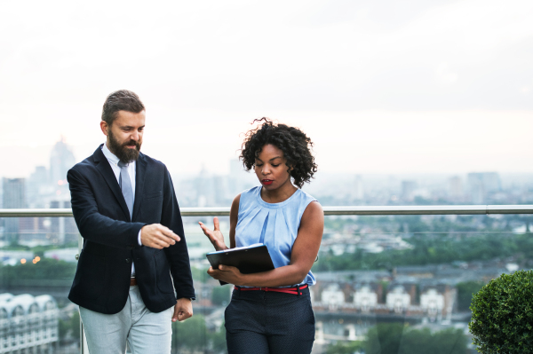 A portrait of businesspeople standing against London rooftop view, discussing something.