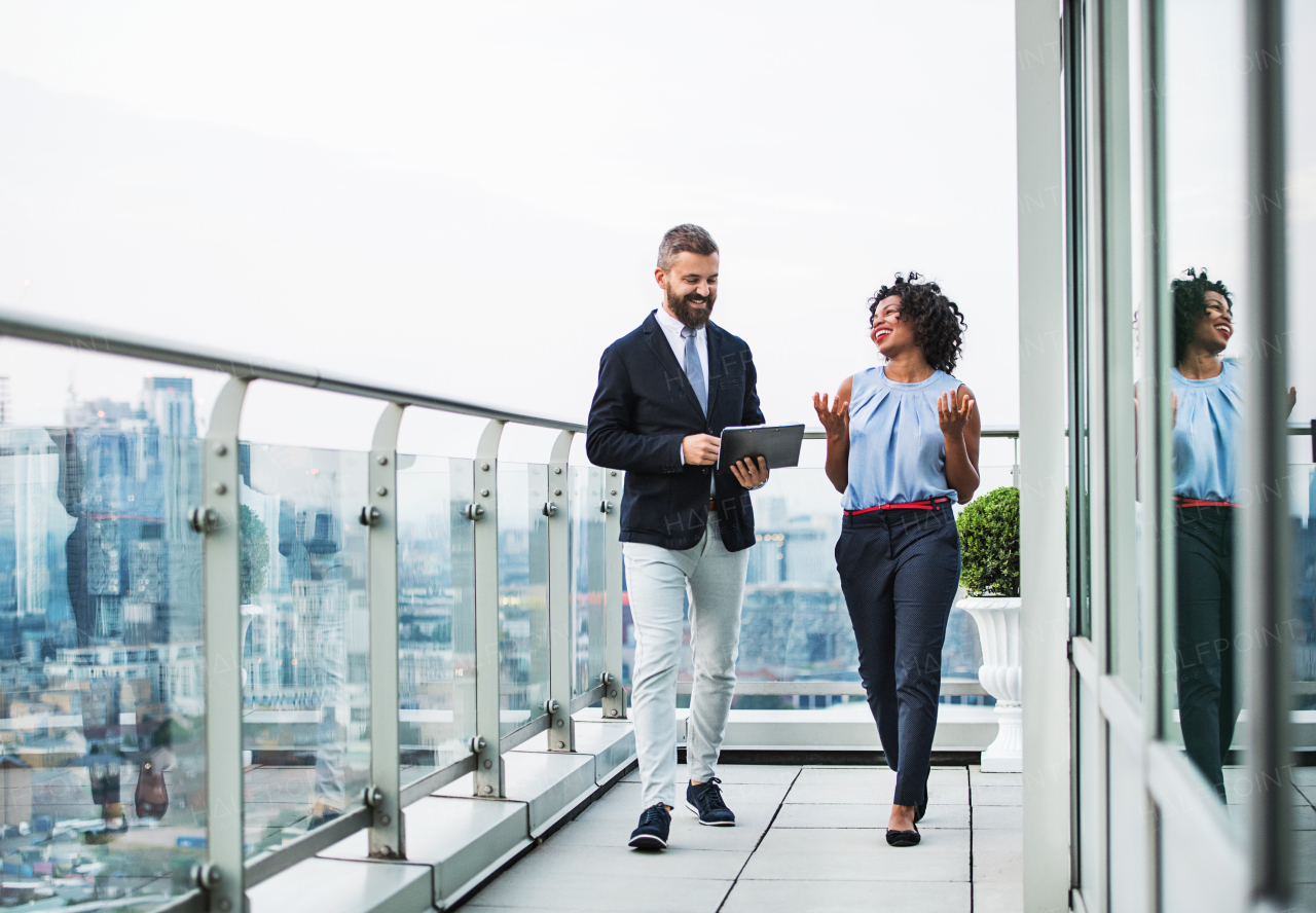 A portrait of businesspeople standing against London rooftop view, discussing something.