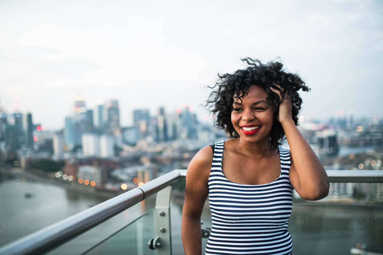 A portrait of black businesswoman standing against London rooftop view panorama. Copy space.