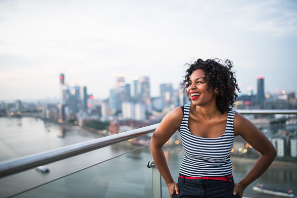 A portrait of black businesswoman standing against London rooftop view panorama. Copy space.