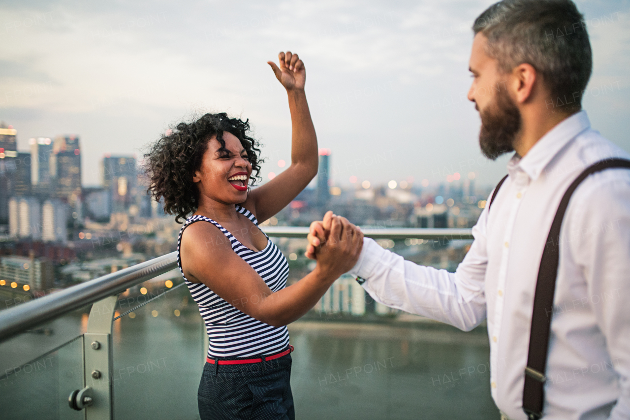 A portrait of businesspeople standing against London rooftop view panorama at sunset, laughing and expressing excitement.