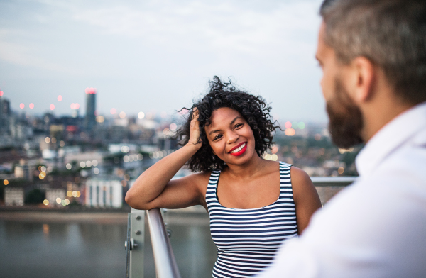 A portrait of businesspeople standing against London rooftop view panorama, talking.