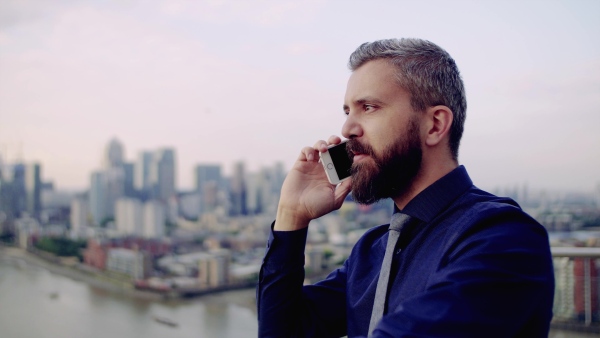 A video of businessman with smartphone standing against London view panorama.