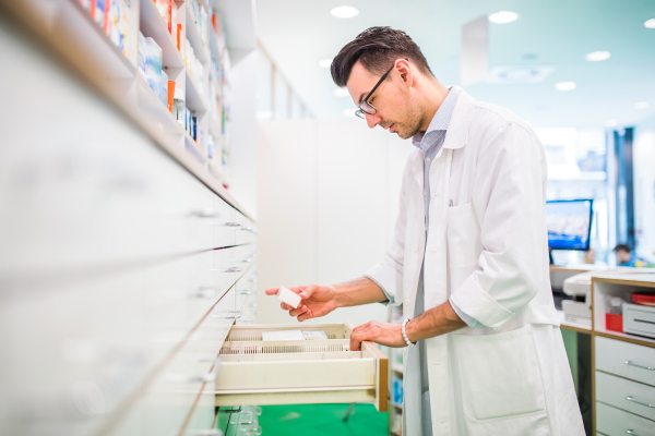 Portrait of a young atrractive friendly male pharmacist, working.