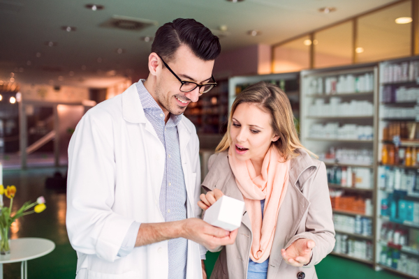 Handsome male friendly pharmacist serving a female customer.