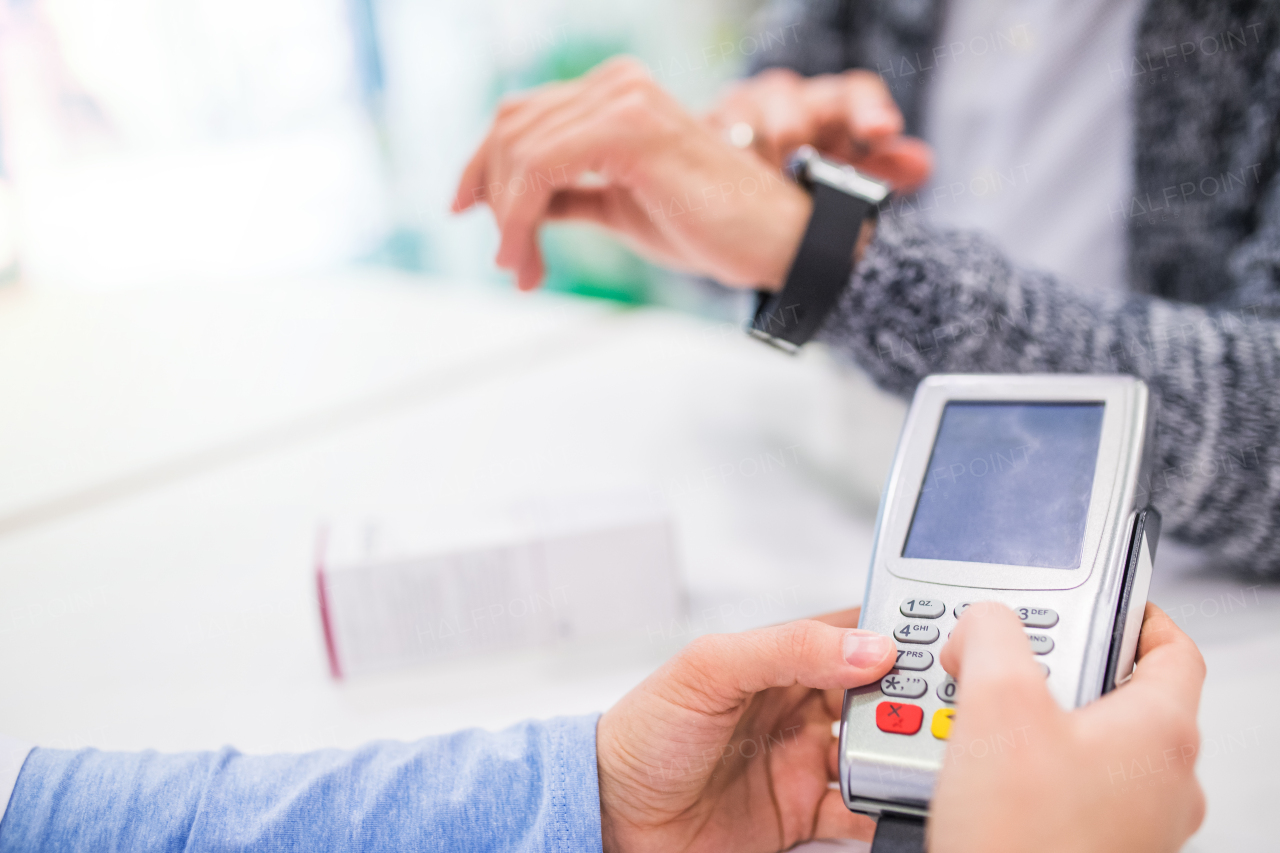 Unrecognizable pharmacist serving a customer. Card payment.