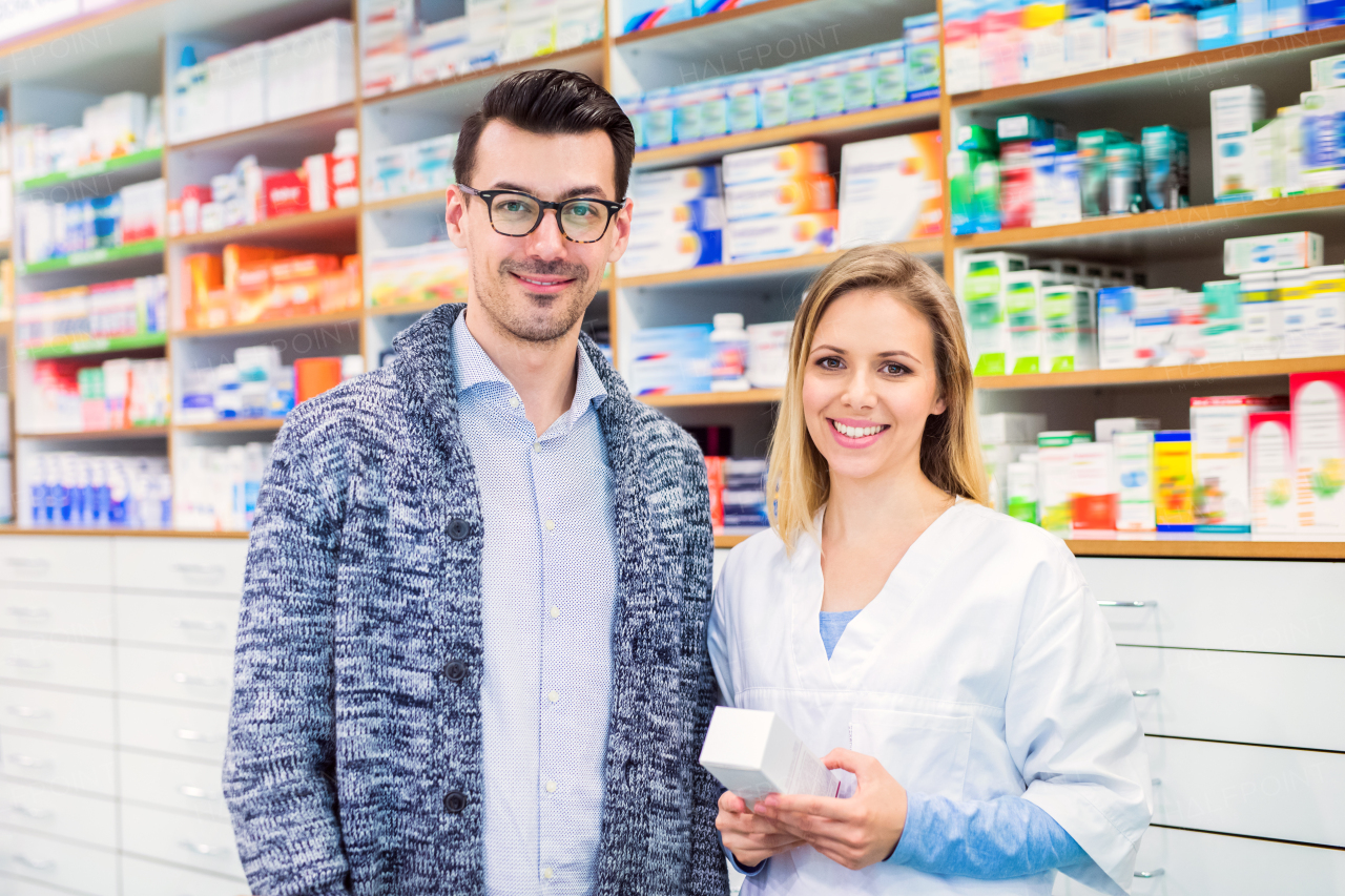 Portrait of a female friendly pharmacist with a male customer or a colleague.